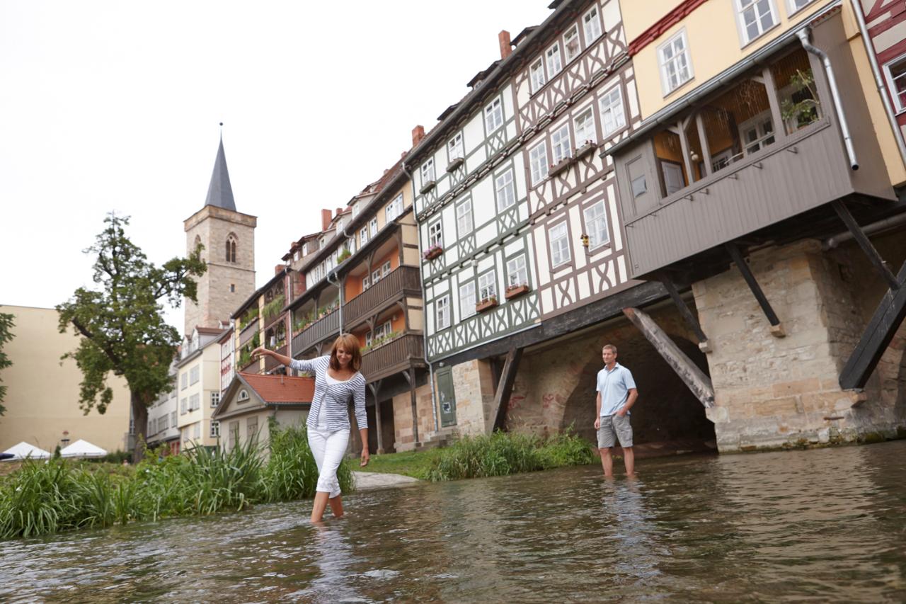 Paar taucht Beine im kühlen Wasser der Gera an der Krämerbrücke in Erfurt