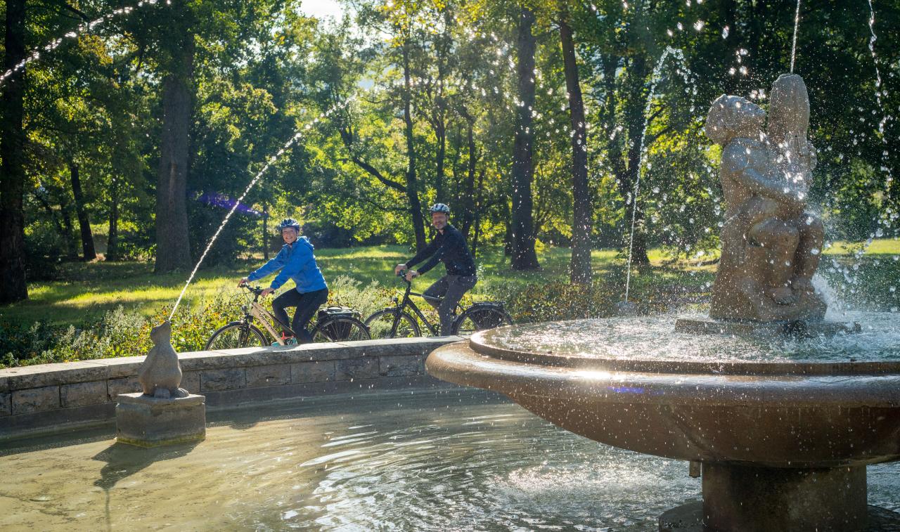 Fahrradfahrer am Märchenbrunnen im Paradiespark in Jena